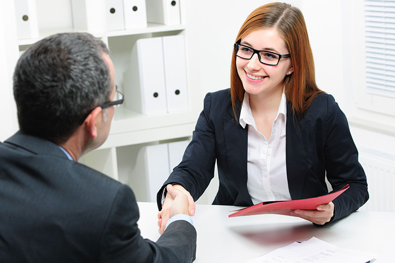 female and male shaking hands at desk